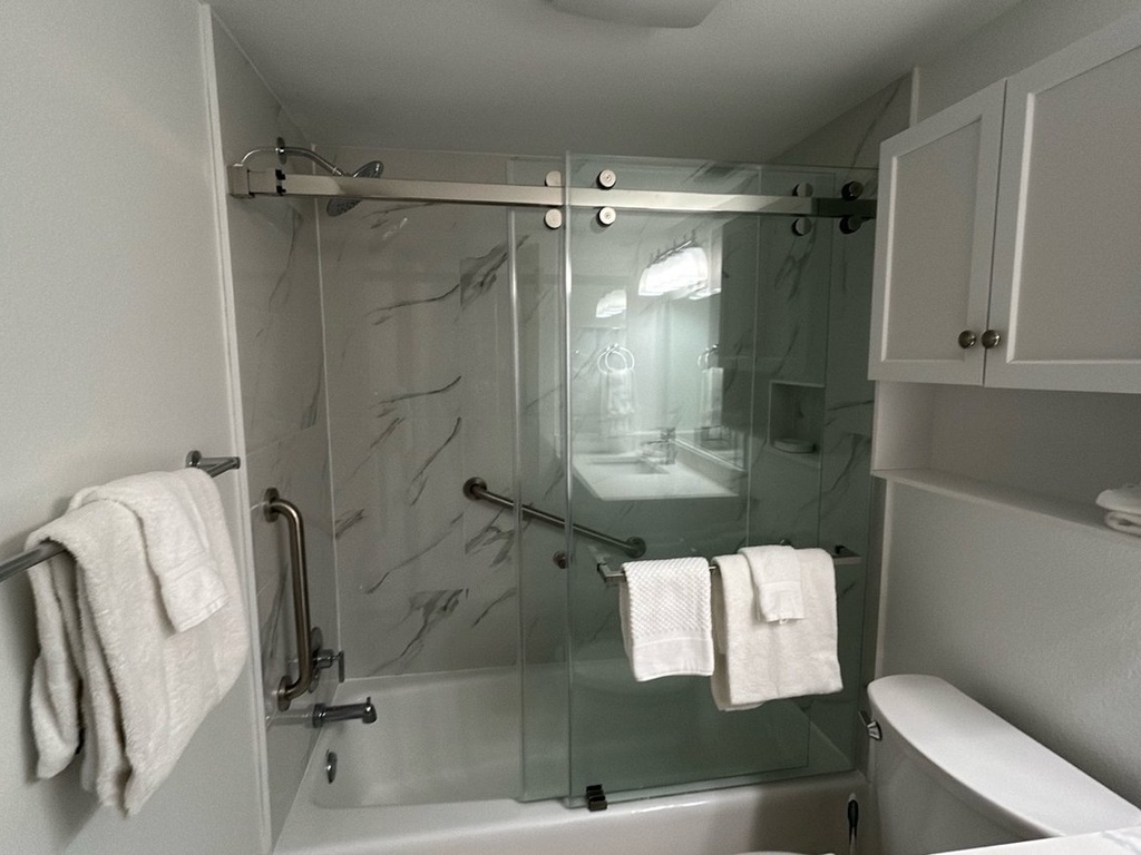 Your sleek modern bathroom features a spacious glass shower with marble-look walls and fresh towels ready for your arrival.