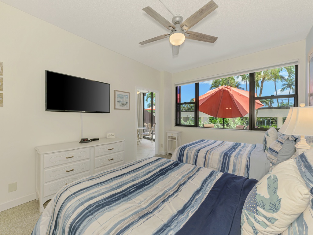 Your bright bedroom features tropical views, ceiling fan, flat-screen TV, and coastal-inspired blue striped bedding for restful nights.