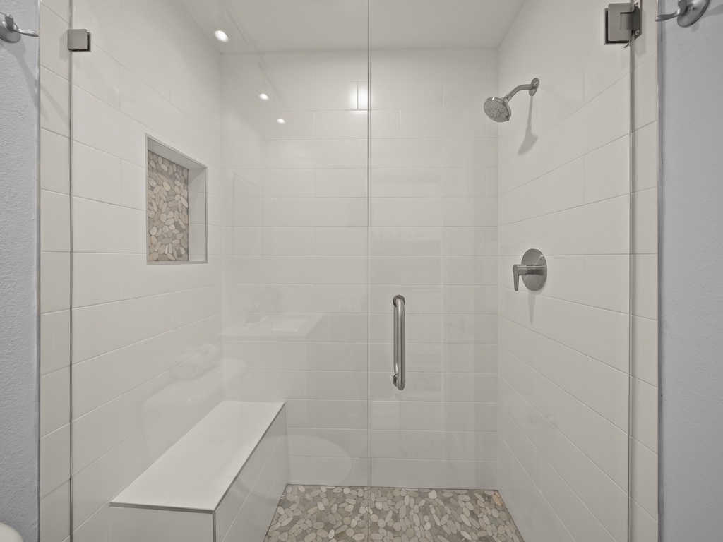 Step into your spacious glass-enclosed shower with modern fixtures, stone accents, and thoughtful built-in seating for ultimate comfort.