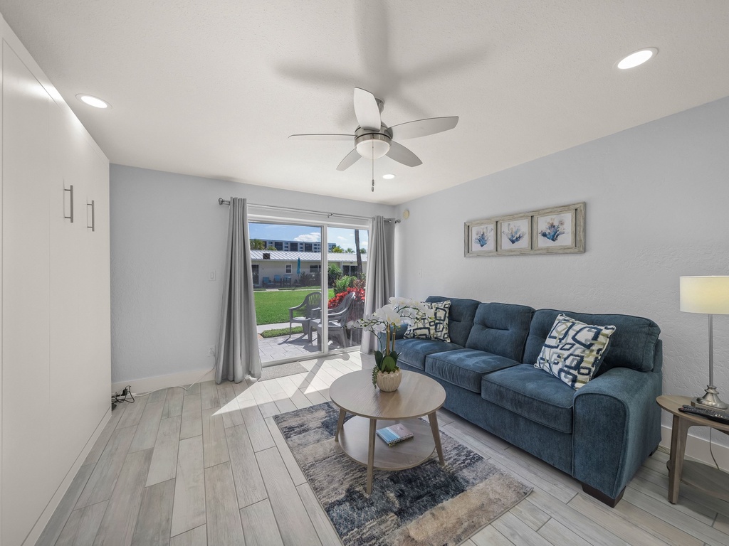 Relax in your bright living space with cozy blue sofa, ceiling fan, and direct patio access to your private yard.