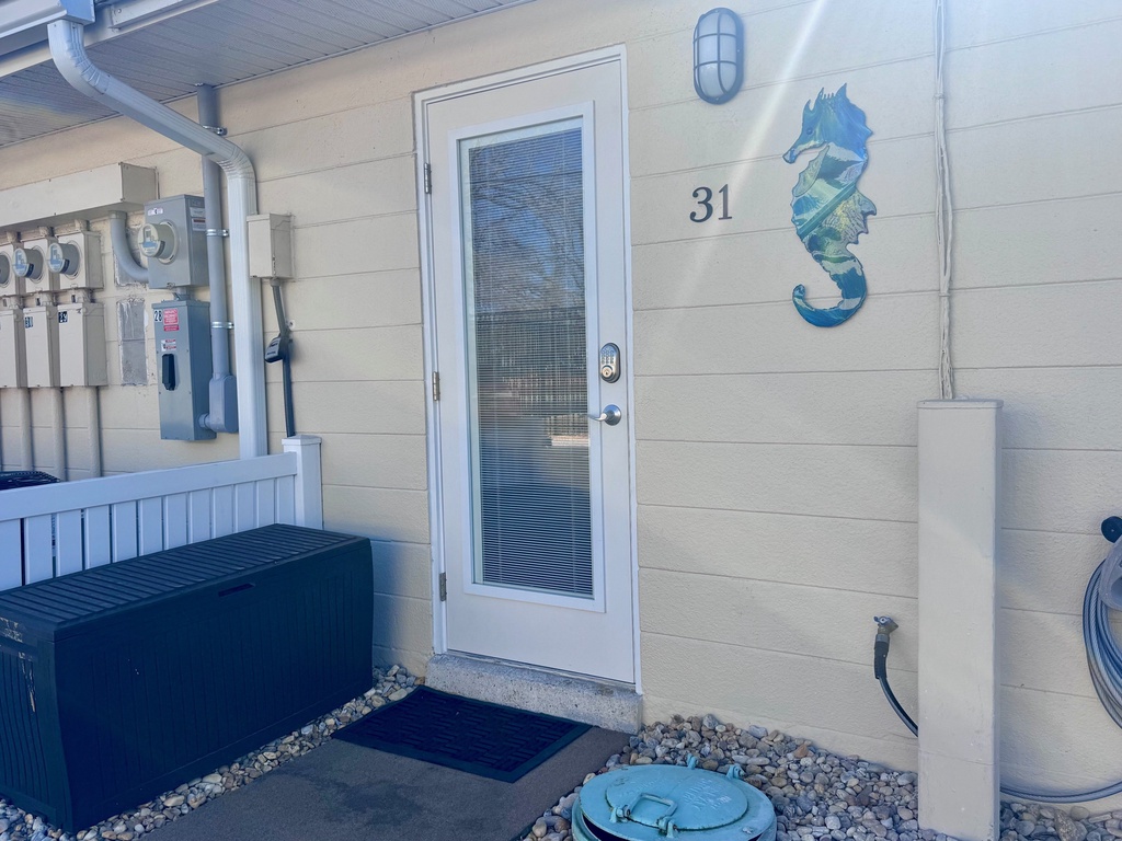 Property entrance at unit 31 featuring coastal-themed seahorse artwork and modern amenities.