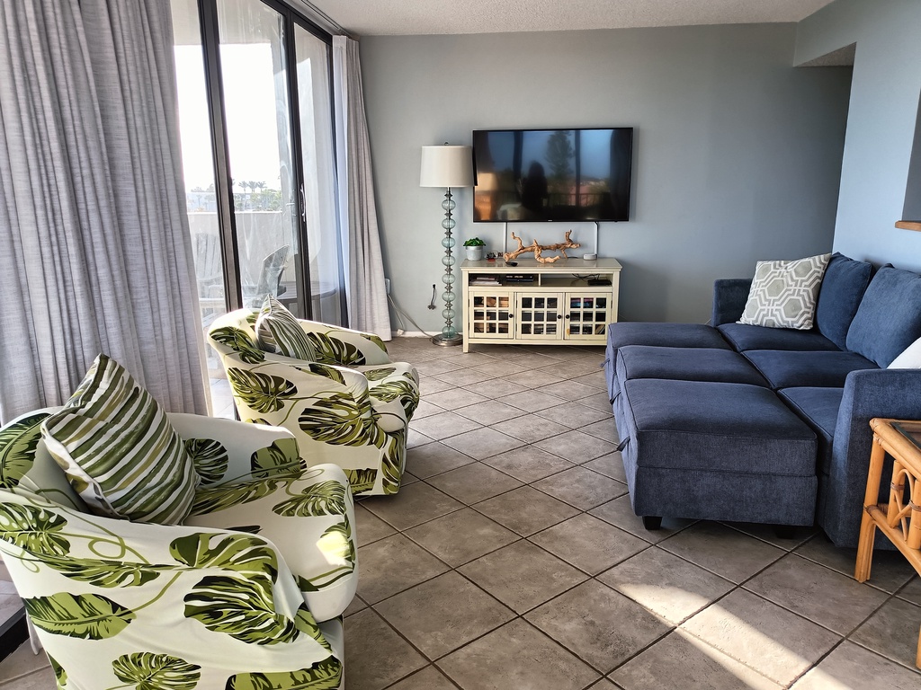 Relax in your bright living room with comfy sectional, tropical accents, and entertainment center - perfect for unwinding after beach days.