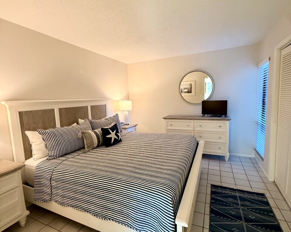 Drift off in your comfortable bedroom with crisp nautical bedding and peaceful natural light streaming through the window.