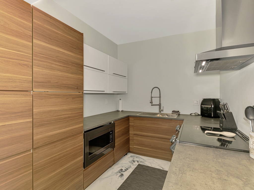 Your sleek modern kitchen features warm wood cabinetry and premium appliances, perfect for creating memorable meals during your stay.