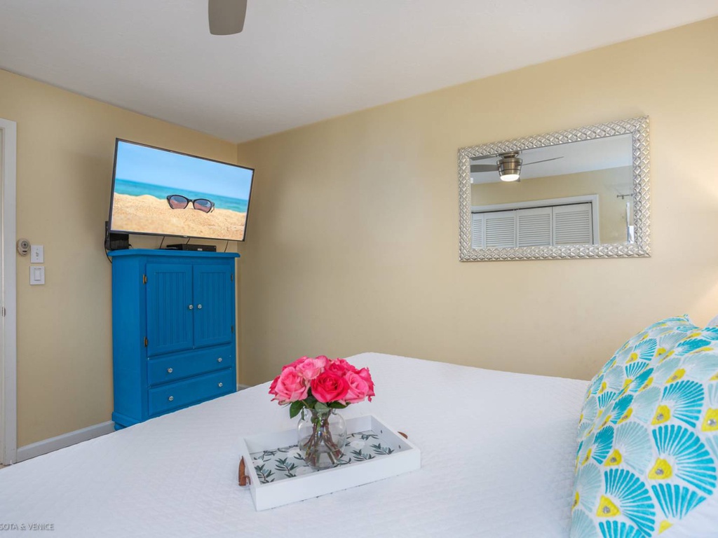 Your bright bedroom features a wall-mounted TV and colorful coastal decor that perfectly complements your beachside getaway.