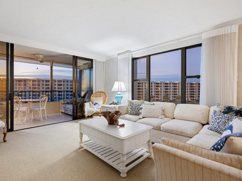 Sink into plush sofas while ocean views stretch endlessly beyond your private balcony in this bright, coastal-inspired living space.