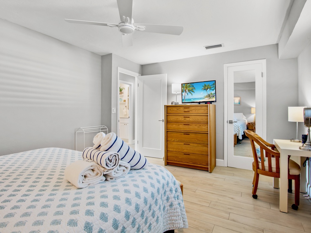 Unwind in your serene bedroom featuring coastal-chic decor, ceiling fan comfort, and entertainment on demand.