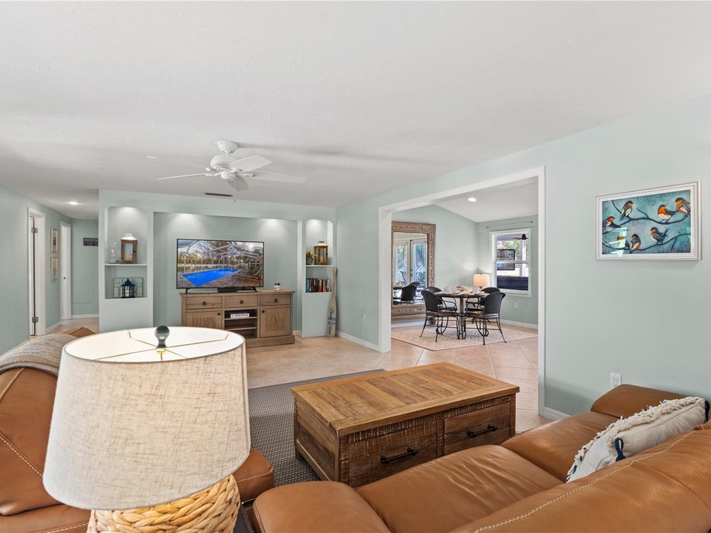 Relax in your spacious living room with plush leather seating, entertainment center, and calming coastal decor that creates the perfect retreat.