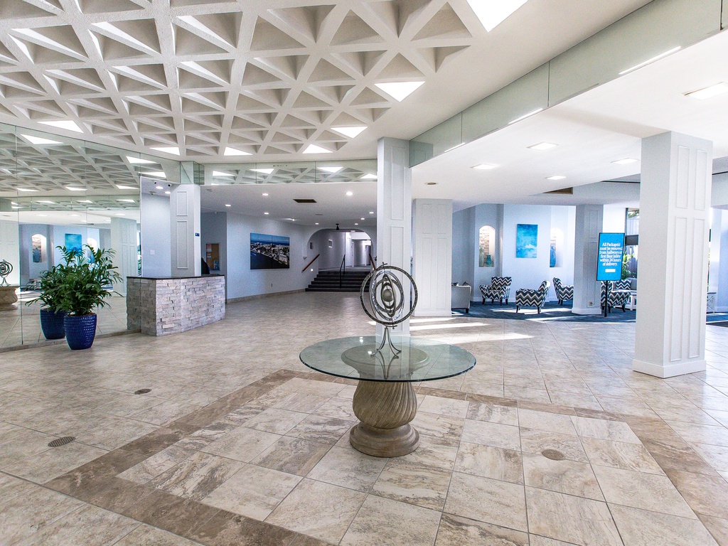 Spacious hotel lobby featuring modern design with geometric ceiling, marble floors, and elegant seating areas for guest comfort.