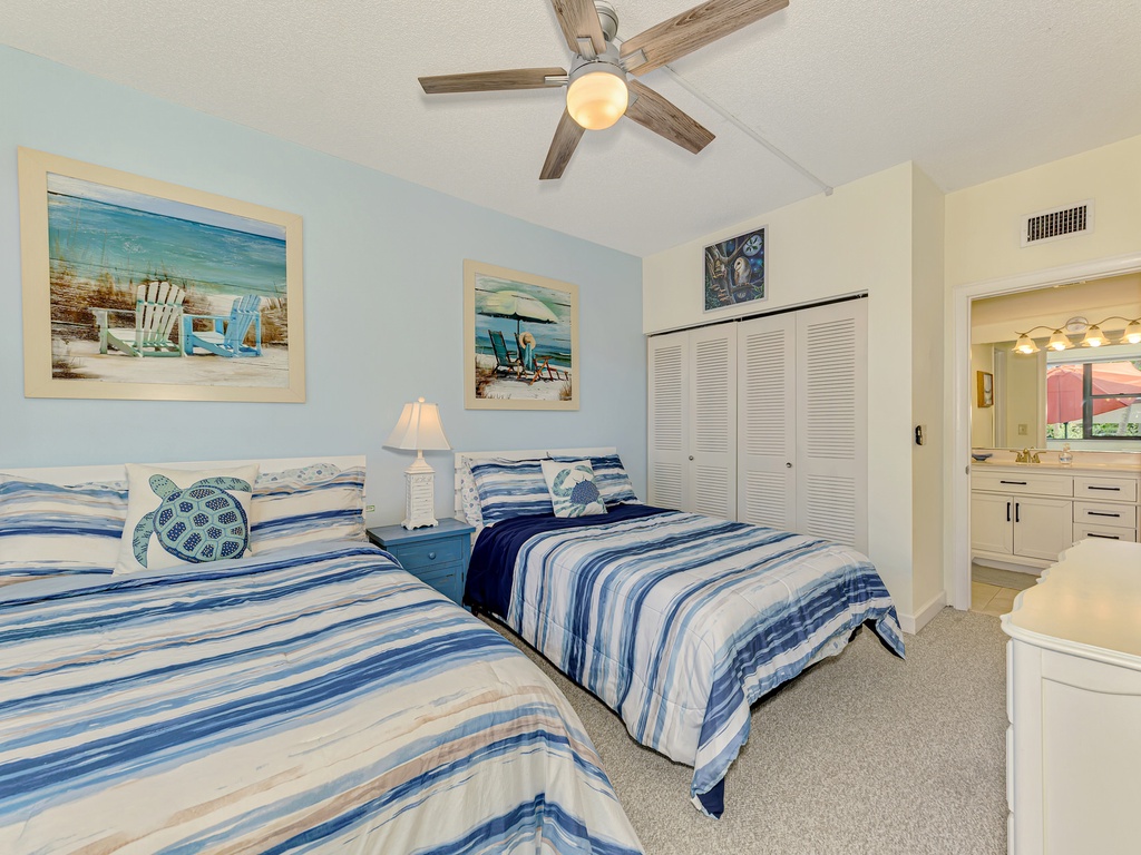 Relax in your coastal-themed twin bedroom with soft blue stripes, beach artwork, and an ensuite bathroom for comfort.