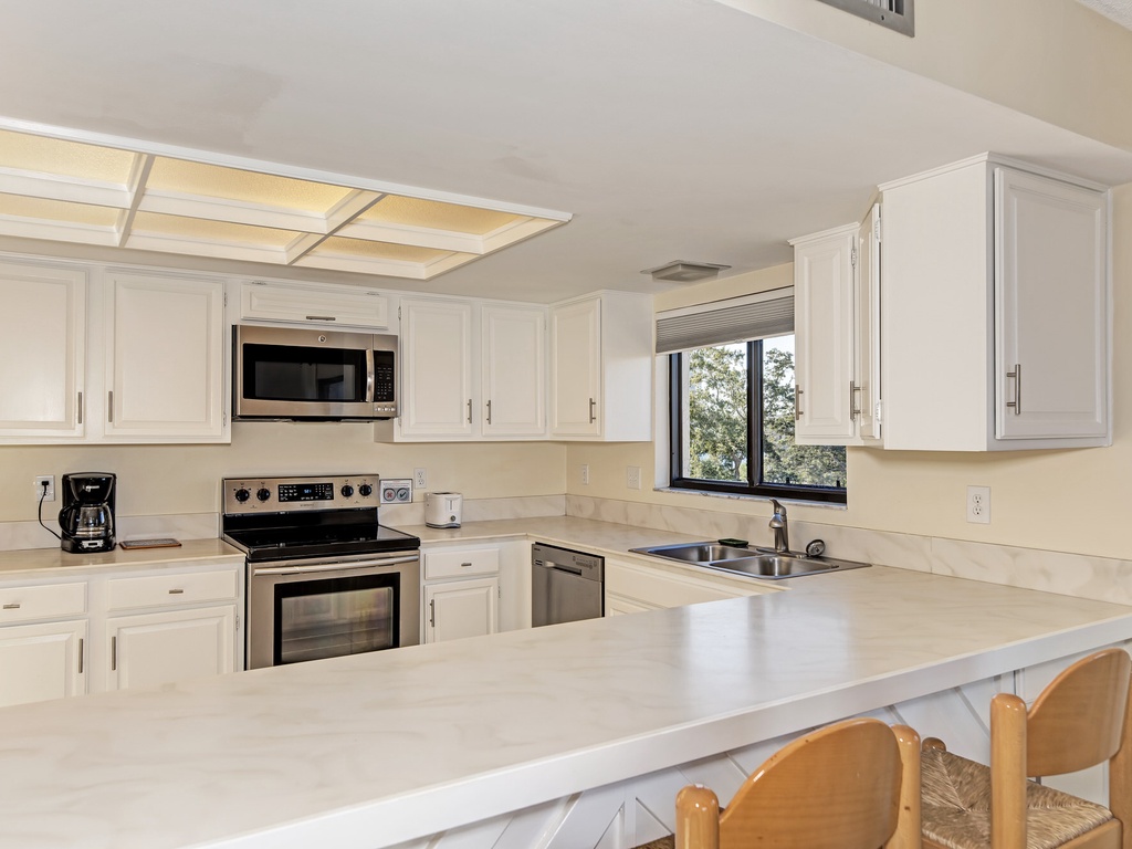 Your fully equipped kitchen invites culinary adventures with pristine white cabinets, modern appliances, and a spacious breakfast bar for morning coffee.