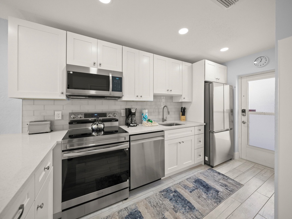 Your fully equipped kitchen features crisp white cabinets, stainless steel appliances, and clean countertops—perfect for preparing home-cooked meals during your stay.