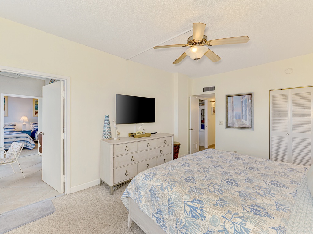 Unwind in your spacious bedroom with coastal-themed bedding, ceiling fan for comfort, flat-screen TV, and plenty of storage space.