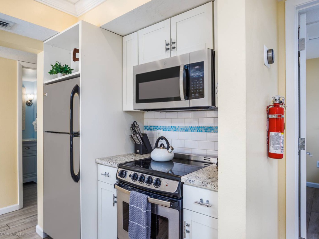 Your compact kitchen has everything you need - full-size appliances, granite counters, and charming blue tile accents for easy meal prep.