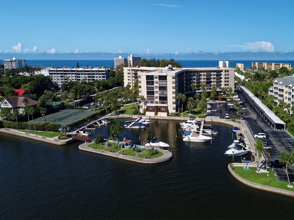 Waterfront community featuring marina access, resort-style buildings, and tropical landscaping near pristine coastal waters.