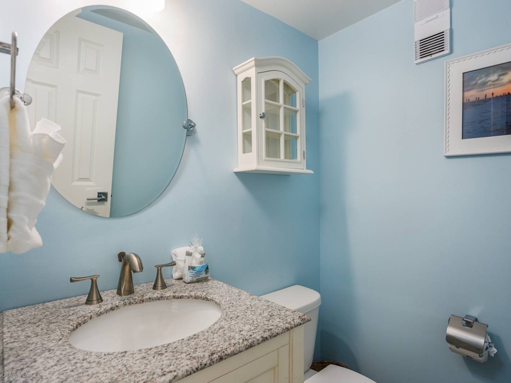 Step into your serene powder room where soft blue walls and granite countertops create a peaceful coastal vibe for refreshing moments.