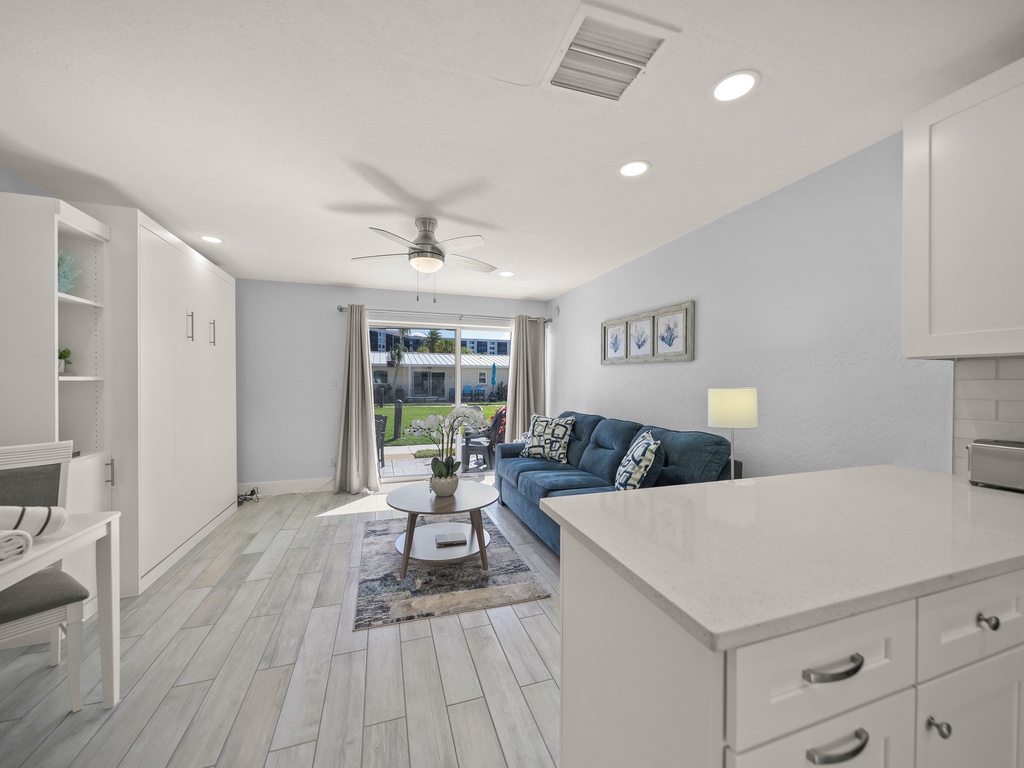 Your stylish open-concept living space flows seamlessly from kitchen to lounge, featuring modern finishes and a cozy blue sofa perfect for relaxation.