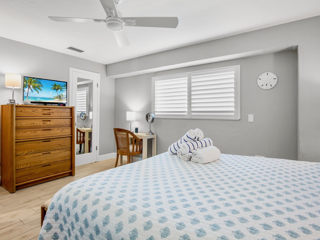 Drift off in your coastal-inspired bedroom featuring soft linens, warm wood furniture, and a peaceful ceiling fan breeze.