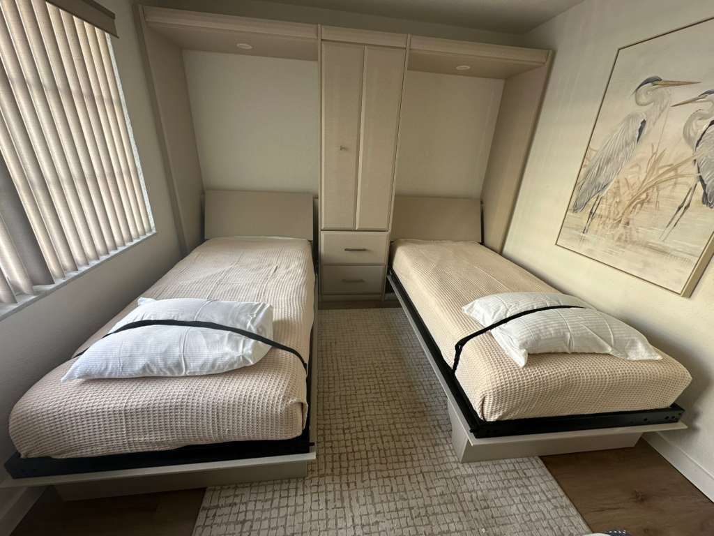 Relax in your cleverly designed bedroom featuring twin Murphy beds with crisp linens, perfect for maximizing space while ensuring comfort.
