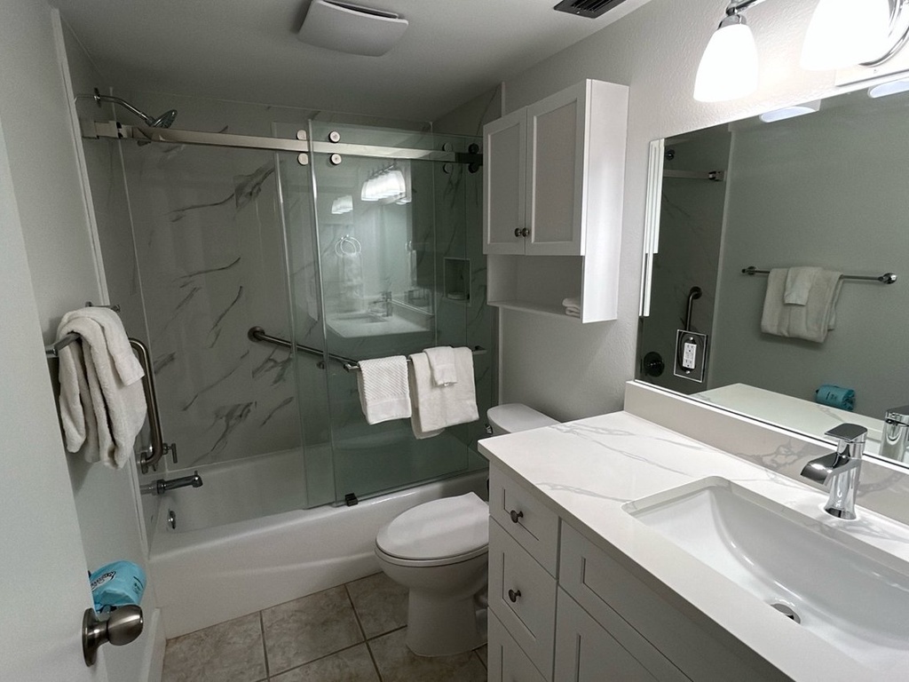 Step into your modern bathroom featuring a sleek glass shower, marble-style walls, and pristine white vanity with premium fixtures.
