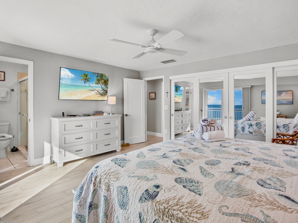 Wake up to ocean views through your private balcony doors in this coastal master suite with tropical touches and modern comfort.