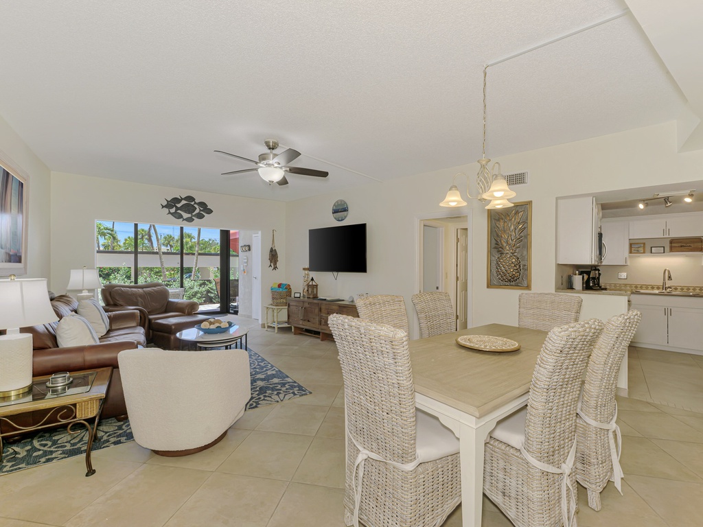 Your open-concept living space seamlessly blends comfort and coastal style, with wicker dining chairs and leather sofas perfect for relaxing.