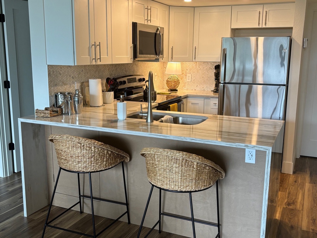 Cook your favorite meals in this modern kitchen featuring stainless steel appliances, elegant white cabinetry, and a convenient breakfast bar for casual dining.