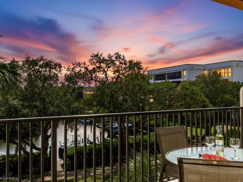 Spectacular sunset views from a private balcony with outdoor dining setup overlooking lush tropical scenery.
