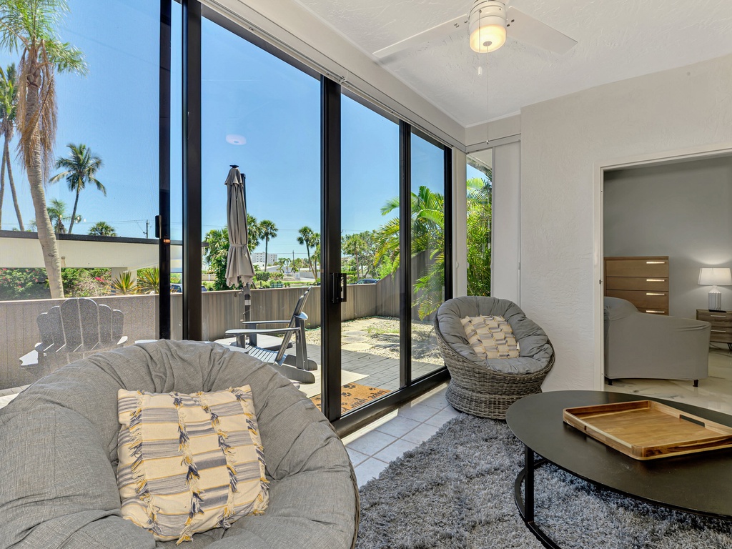 Unwind in your stylish living space where floor-to-ceiling windows frame tropical palms, creating a seamless indoor-outdoor flow.