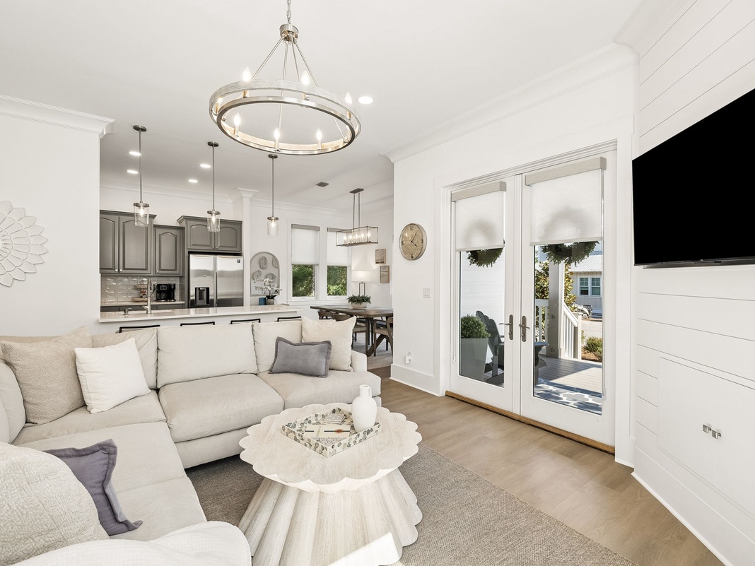 Sink into plush sofas in your open living space, where soft light floods through glass doors leading to your private outdoor retreat. Modern comforts blend with coastal charm.