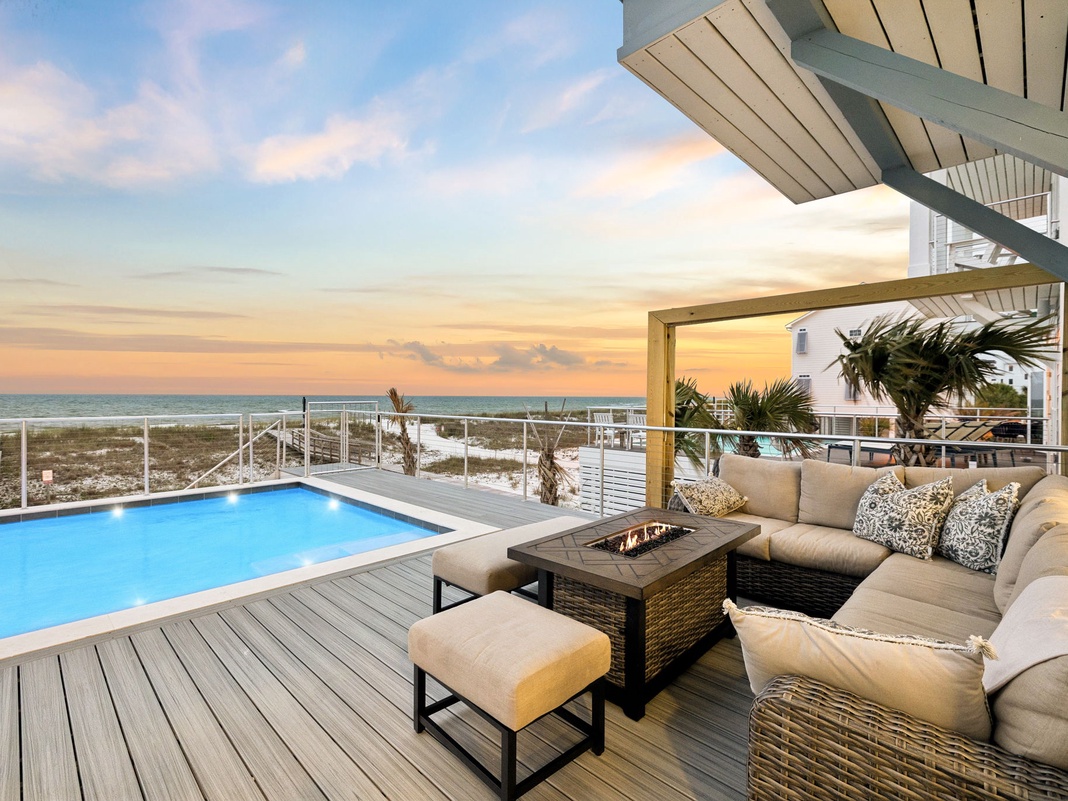 A stunning beachfront property featuring a private pool and outdoor lounge area, with direct coastal access and panoramic ocean views at golden hour.
