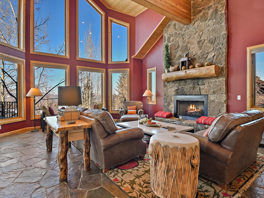 Unwind in your cozy living room where leather seating faces a crackling stone fireplace and soaring windows frame stunning views.