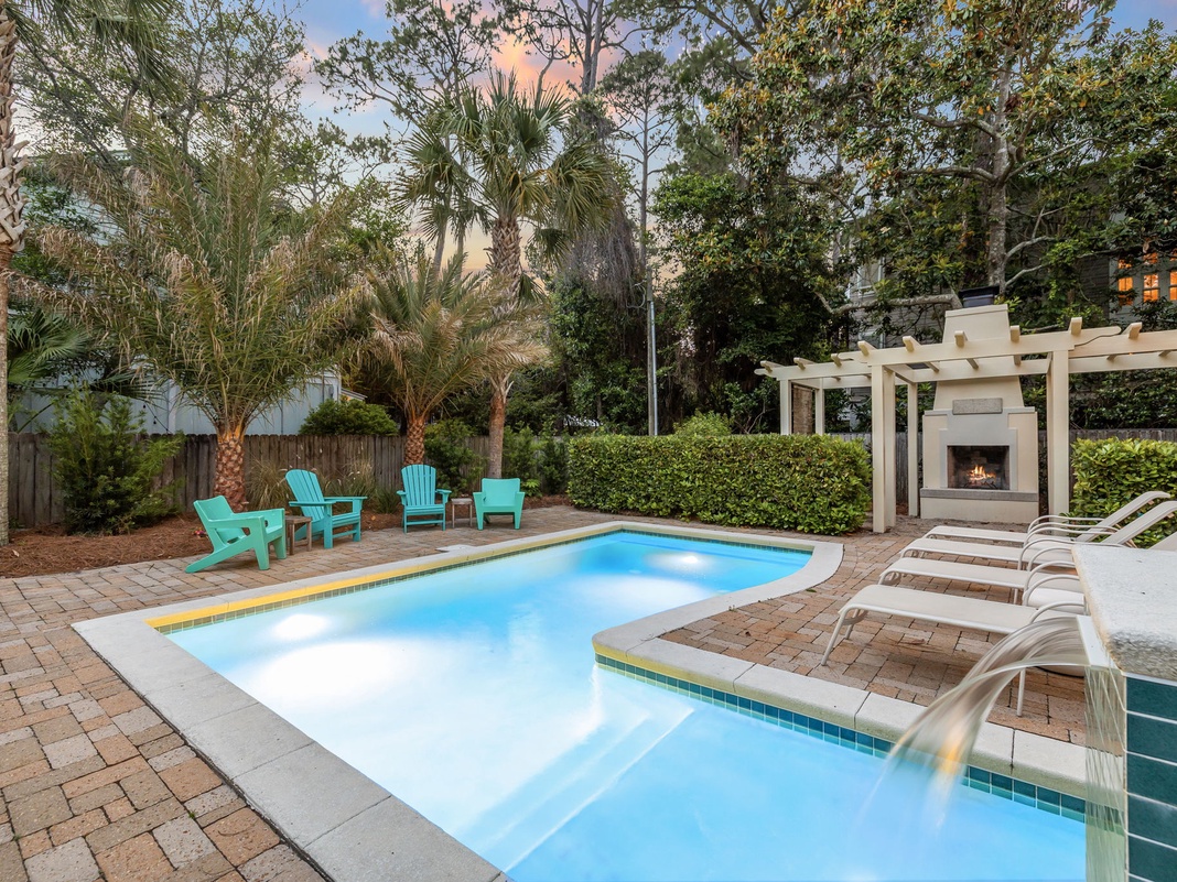 Lounge poolside in vibrant turquoise chairs, soak in the spa, or unwind by the outdoor fireplace surrounded by swaying palms and a peaceful garden setting.