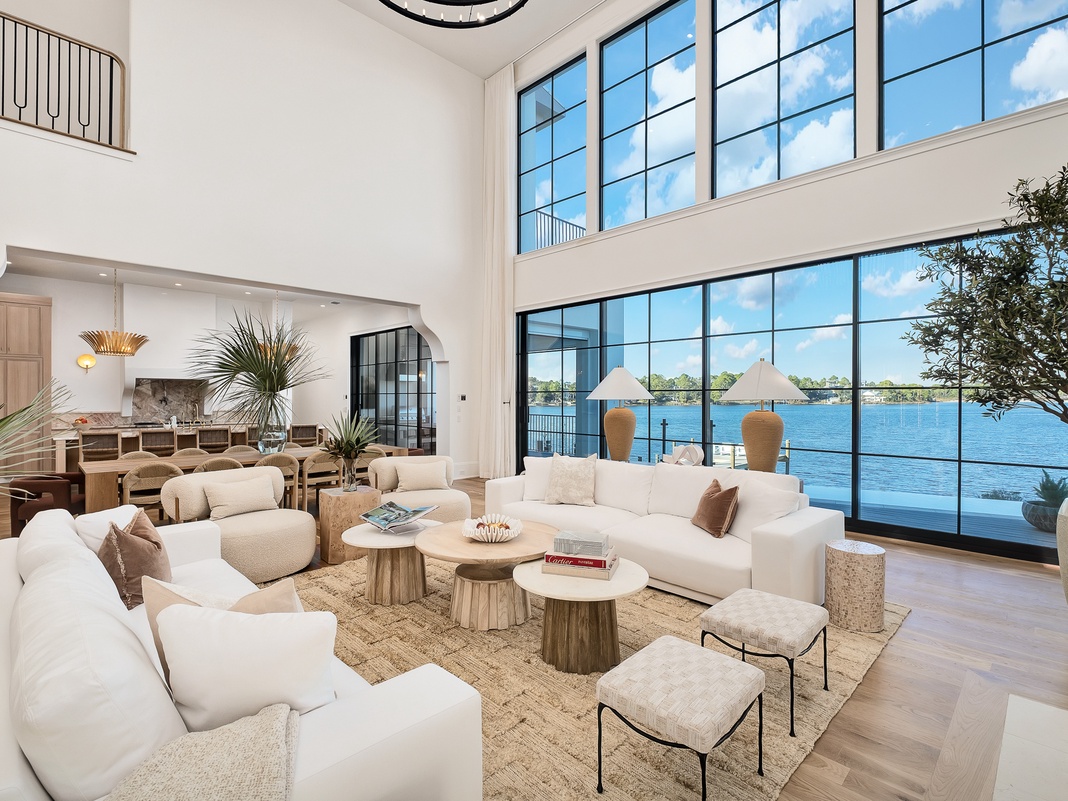 Sink into plush white sofas as natural light floods your waterfront living space through floor-to-ceiling windows.