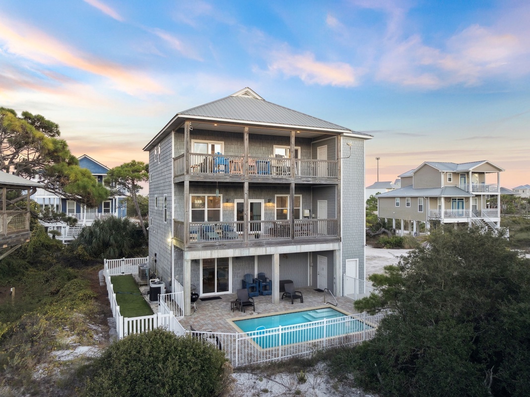 Multi-level coastal home with private pool, spacious decks, and surrounded by lush vegetation in a peaceful beach community.