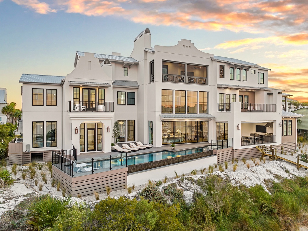 Stunning beachfront estate featuring modern architecture, infinity pool, and panoramic ocean views at golden hour.