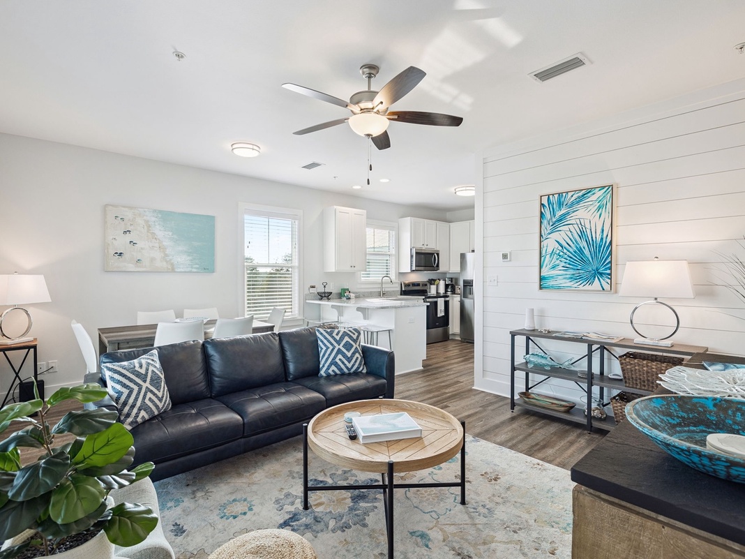 Relax in your bright, coastal-inspired living space featuring a comfy leather sofa, tropical artwork, and modern amenities.