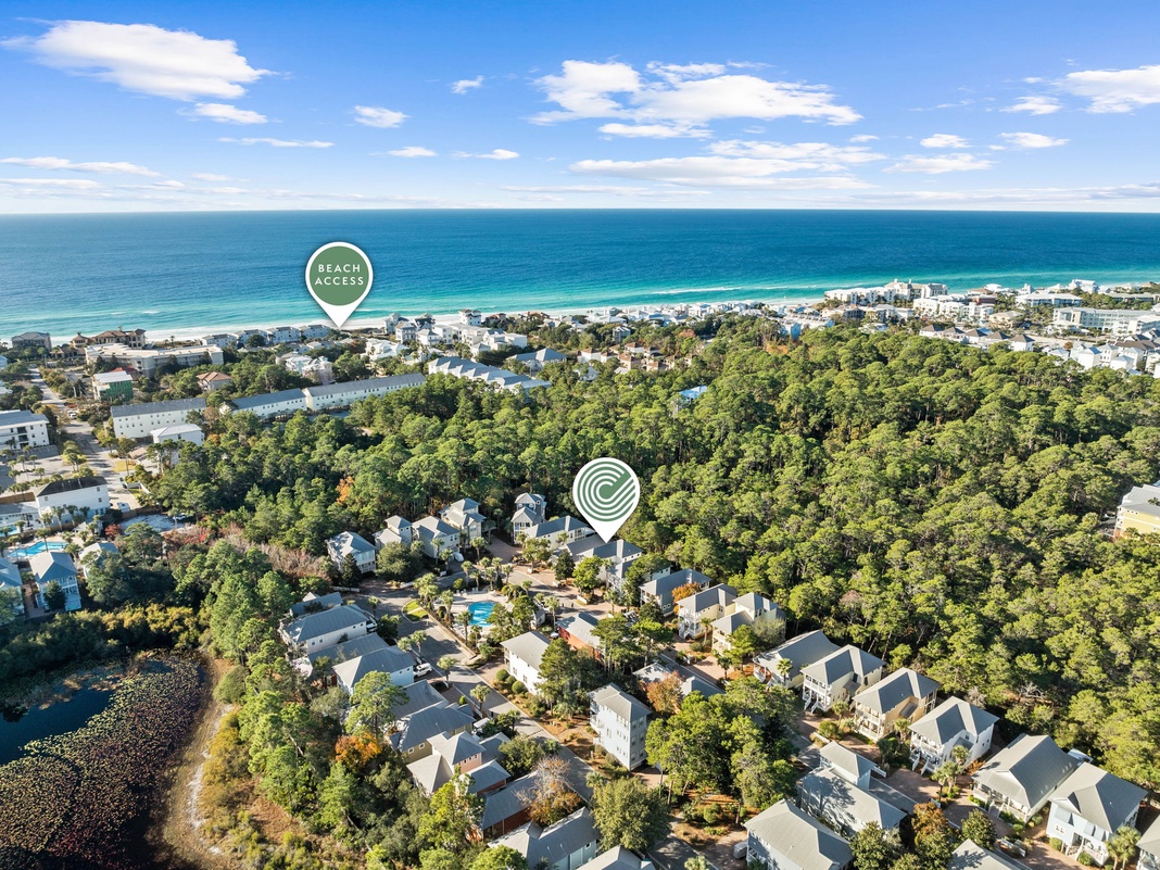 Aerial view showcasing the property's location in a treed residential area near pristine beaches and turquoise waters.