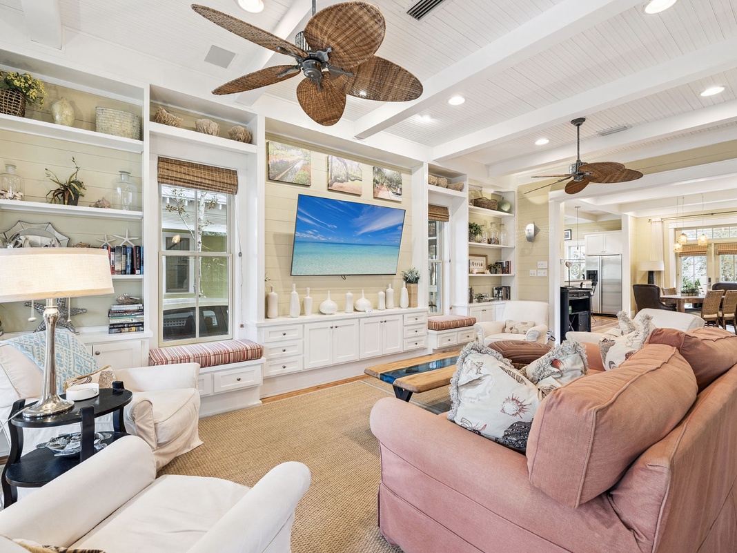 Relax in your elegantly appointed living room, where coastal style meets comfort with built-in shelving and tropical ceiling fans.