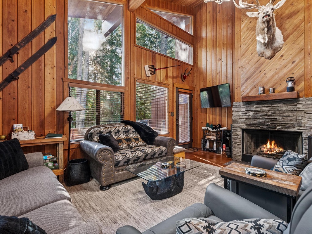 Cozy up by the crackling fireplace in this rustic living room, where warm wood walls and comfortable seating create your perfect mountain retreat.