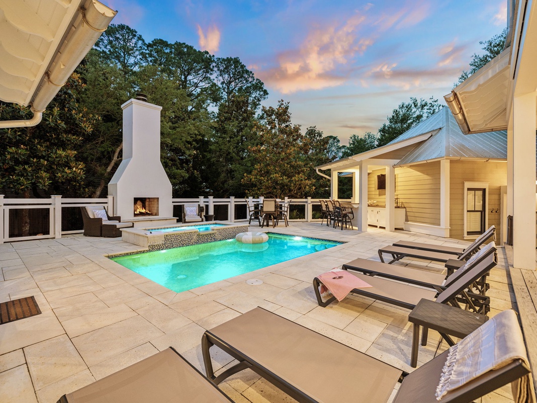 Stunning private pool and covered patio invite you to unwind under soft evening skies, where a crackling outdoor fireplace and plush lounge chairs await your perfect escape.