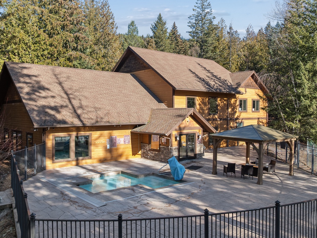 Mountain lodge featuring private pool and covered outdoor dining pavilion surrounded by towering evergreen forest.