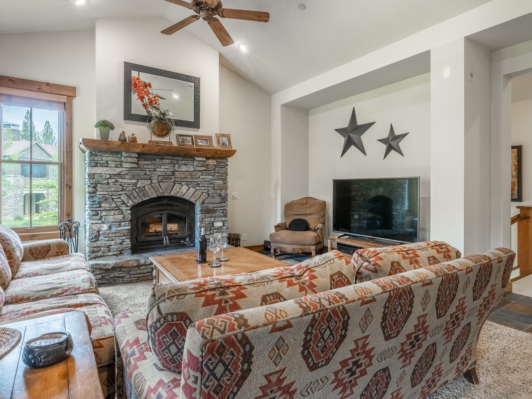 Sink into plush sofas by the stone fireplace and gather around your entertainment center in this inviting living room, where high ceilings and warm wood accents create the perfect mountain retreat for your group.