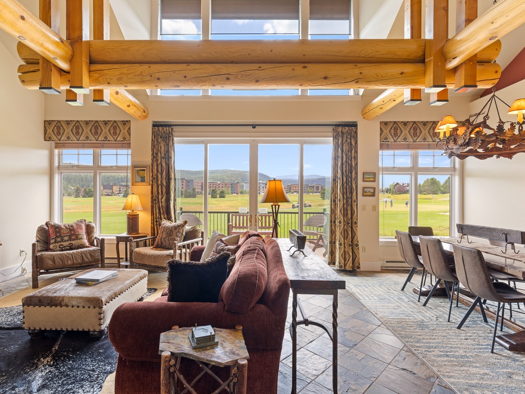 Picture yourself relaxing in this stunning great room, where soaring timber beams frame expansive golf course views. Cozy up by the fireplace or gather around the dining table—your mountain retreat awaits.