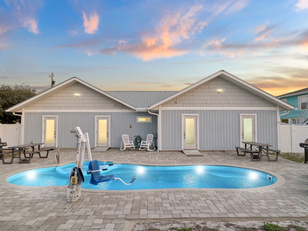 Stunning vacation rental with private pool and patio seating areas at sunset.