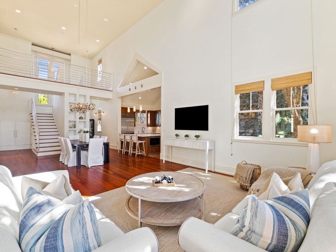 Sink into plush white sofas and enjoy the soaring ceilings in this bright, airy living space with gleaming hardwood floors and modern elegance.
