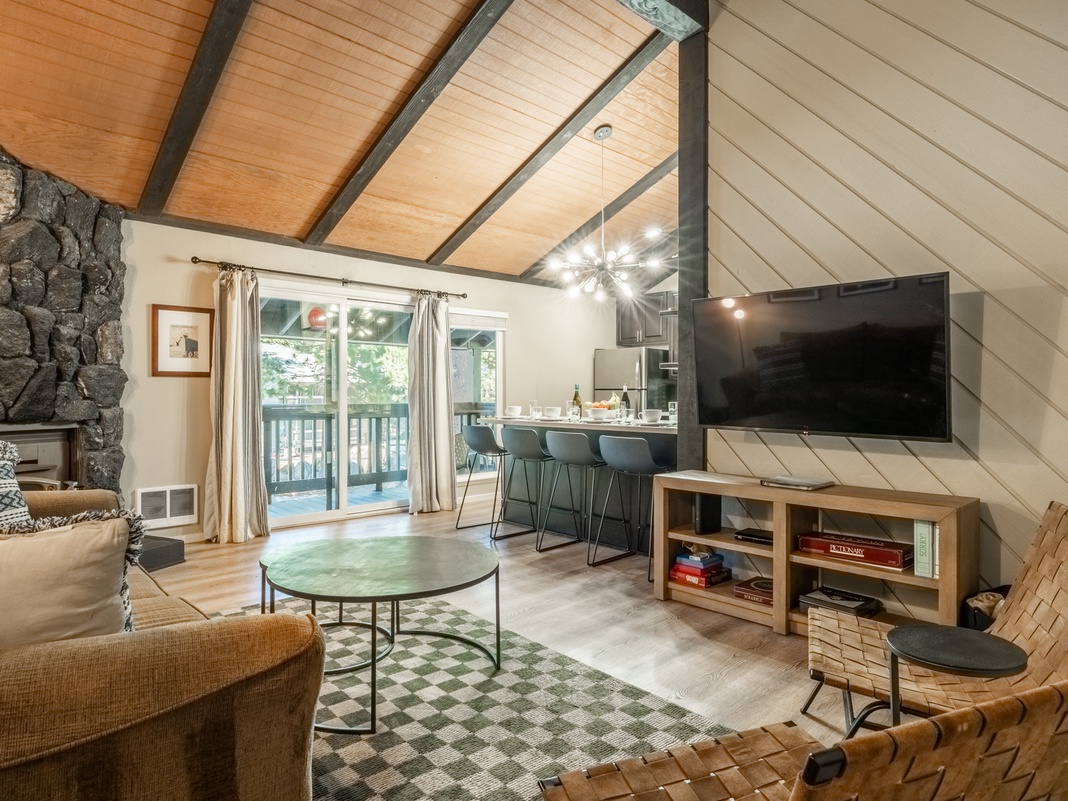 Unwind in this open-concept living space with vaulted wood ceilings and a striking stone fireplace. Relax on cozy seating, cook in the stylish kitchen, and step onto the private balcony for fresh mountain air.