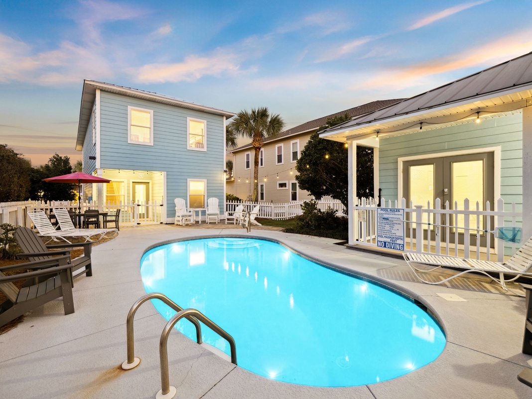 Charming coastal property featuring a private pool surrounded by comfortable lounge chairs and tropical landscaping at twilight.