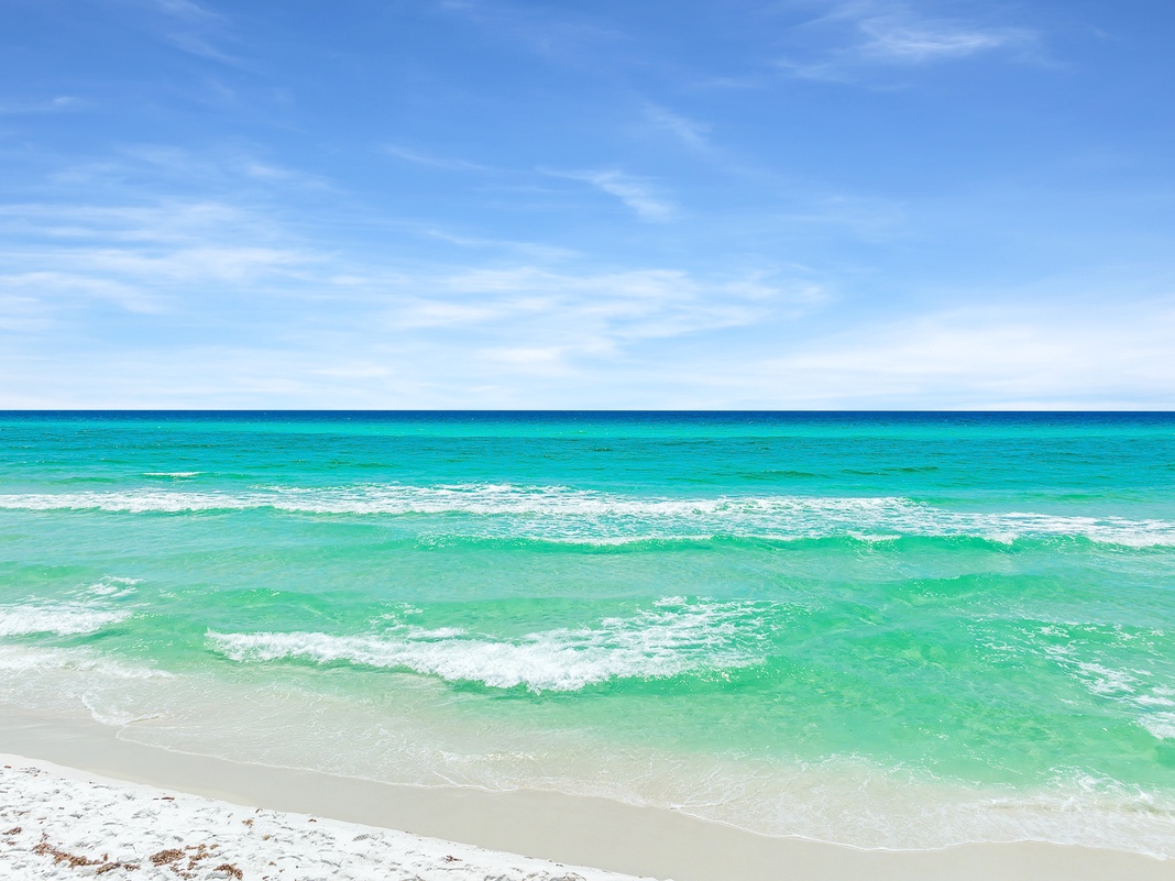 Pristine white sand beach meets turquoise waters under brilliant blue skies, creating the perfect coastal retreat.