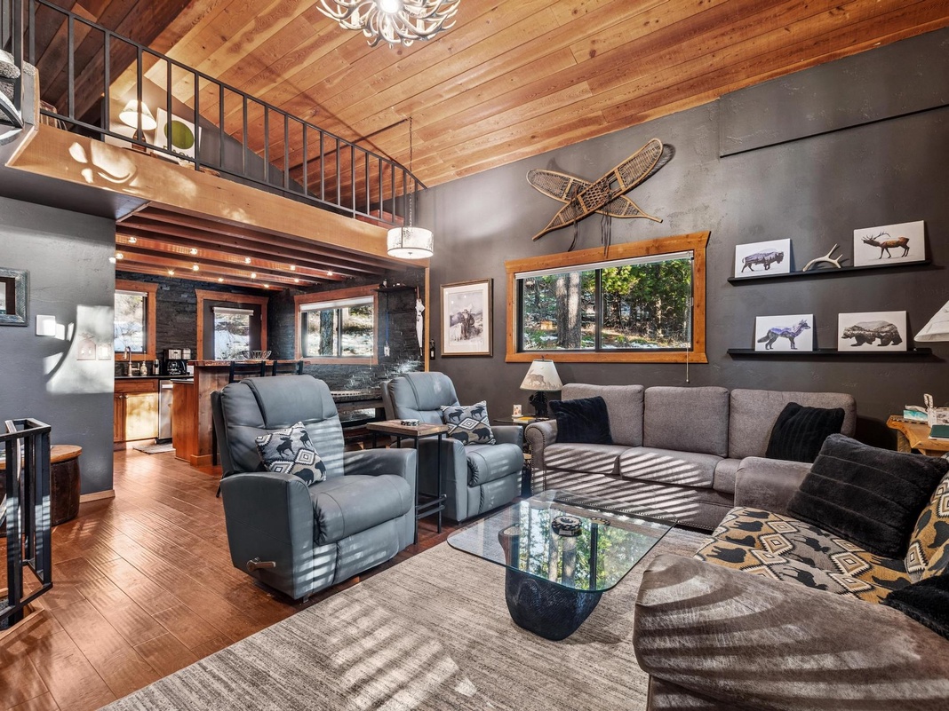 Sink into plush seating beneath soaring wood beam ceilings, where rustic charm meets modern comfort in your mountain retreat's inviting living space.